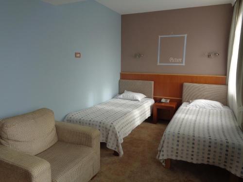 a room with two beds and a couch and a chair at Hotel Park Central in Sliven