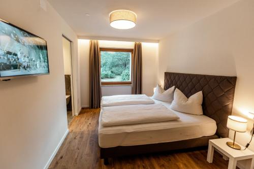 Schlafzimmer mit einem Bett und einem Fenster in der Unterkunft Tyrol Living & Cafe in Welschnofen