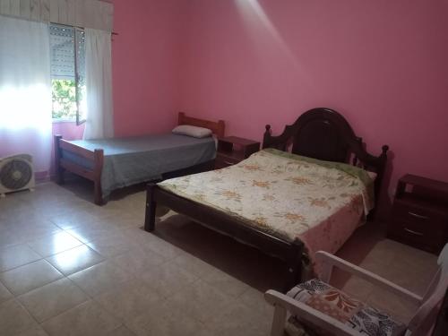 1 dormitorio con 2 camas en una habitación con paredes rosas en Casa en Las Tapias cerca de Villa de Las Rosas en San Javier