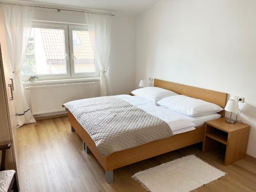 a white bedroom with a bed and a window at Old Town Piešťany Apartments in Piešťany