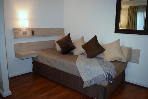 a bed with white pillows and pillows in a room at Apart Hotel Cambiaso in Santiago