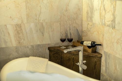 a bathroom with two glasses of wine and a tub at Foremanson Cave Hotel in Nar