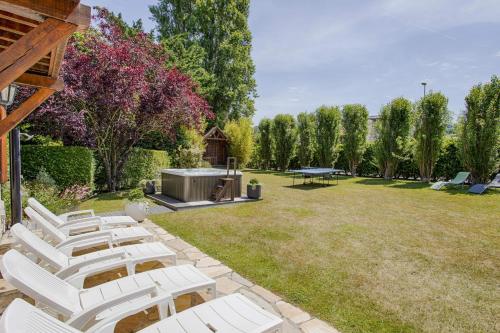 un grupo de sillas blancas sentadas en un patio en La Côte Fleurie - 5 Bdr - Garden & Jacuzzi - Tourgéville Plage en Deauville