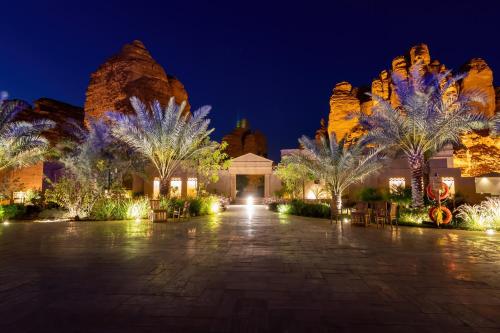 a resort with palm trees and lights at night at Shaden Resort in AlUla