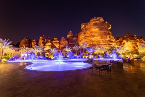 a pool with blue lights in front of a rock formation at Shaden Resort in AlUla