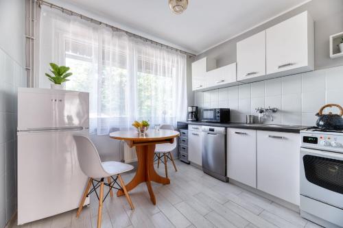 シュクラルスカ・ポレンバにあるApartament Arturro z ogródkiemの白いキャビネット、テーブルと椅子付きのキッチンが備わります。