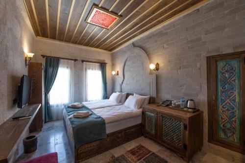 a bedroom with a bed and a television in a room at Foremanson Cave Hotel in Nar