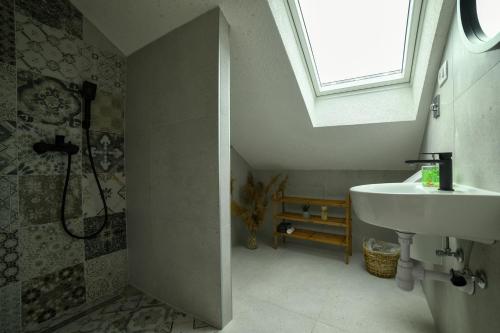 a bathroom with a sink and a shower with a window at Apartman Sinjska Alka in Sinj