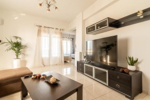 a living room with a large television and a table at Coastal Family House With SeaView in Heraklio Town