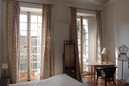 a bedroom with a bed and a desk and windows at Chambre d'hôte du Château in Dourdan