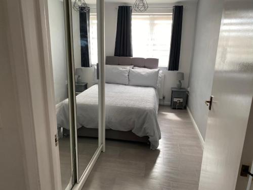 un dormitorio con una cama y un espejo en Modern 2 bedroom flat with Sky TV & free parking, en Dagenham