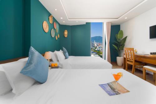 a bedroom with two beds with blue walls and a desk at Merry Land Hotel Da Nang in Danang
