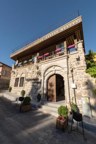 a stone building with a balcony on top of it at Foremanson Cave Hotel in Nar