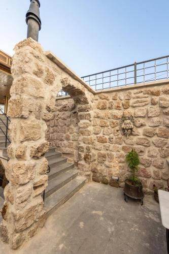 a stone wall with stairs and a potted plant at Foremanson Cave Hotel in Nar