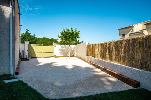 una valla de madera junto a una entrada de hormigón en Le Cabanon de Christine, en LʼIsle-sur-la-Sorgue