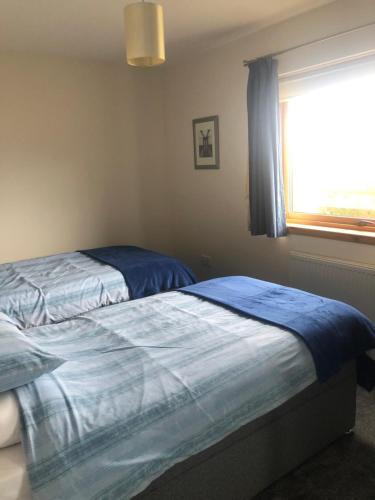 1 dormitorio con cama con sábanas azules y ventana en River Ness View, en Inverness