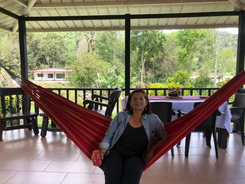a woman sitting in a hammock on a porch at Cabaña tipo glamping en finca cafetera con zonas verdes, avistamiento de aves, paisaje cafetero in San Francisco