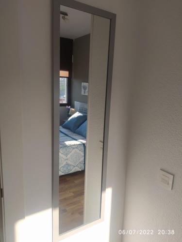 a mirror on a wall with a bed in a bedroom at Piso Navas in Navas de San Antonio