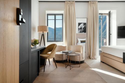 a hotel room with a bed and a table and chairs at MUSA Lago di Como in Sala Comacina