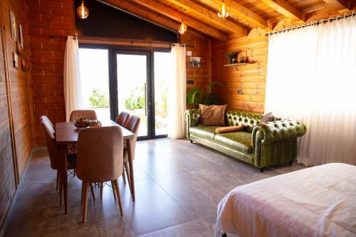 a bedroom with a table and a couch and a room with a bed at Grand Golan Cabins in Buq‘ātā