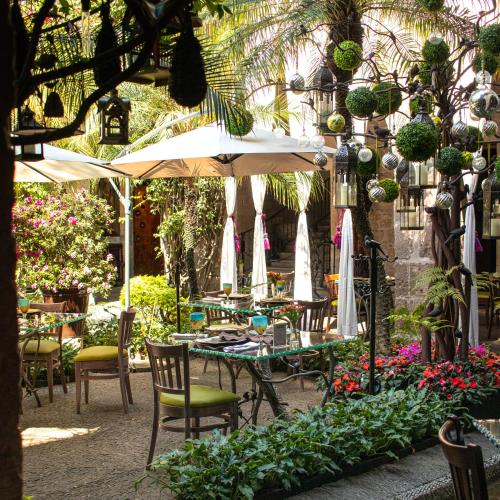 a table with chairs and an umbrella in a garden at Hotel De La Soledad in Morelia
