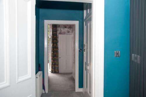 a hallway with blue walls and a white door at Family Apartment - Skye - Private Members Club in Edinburgh