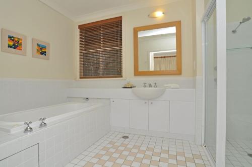 a bathroom with a tub and a sink and a mirror at Villa 1br Villa located within Cypress Lakes Resort in Pokolbin