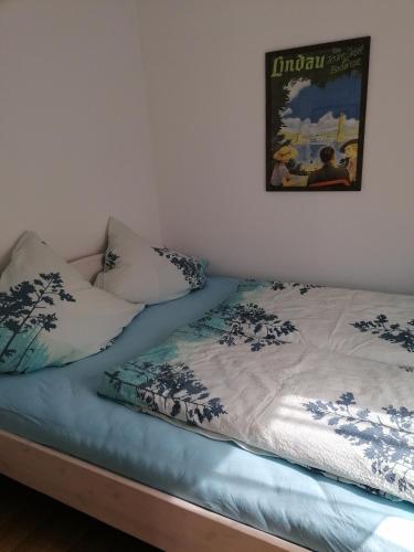 een bed met twee kussens en een foto aan de muur bij Appartement an der Ach Lindau in Lindau