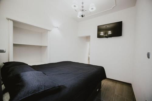 a bedroom with a black bed and a tv on the wall at Kenti Residence in Ljubljana