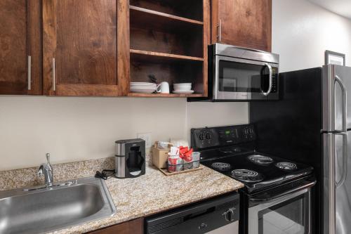 a kitchen with a sink and a stove and a microwave at Home Away Kitchen Suites Enid in Enid