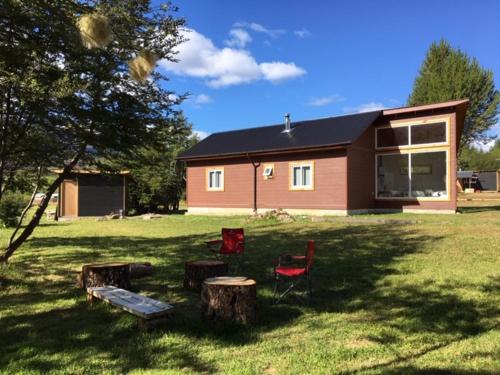 a house with two chairs and a table in a yard at Ribera Cochrane, Cochrane in Cochrane