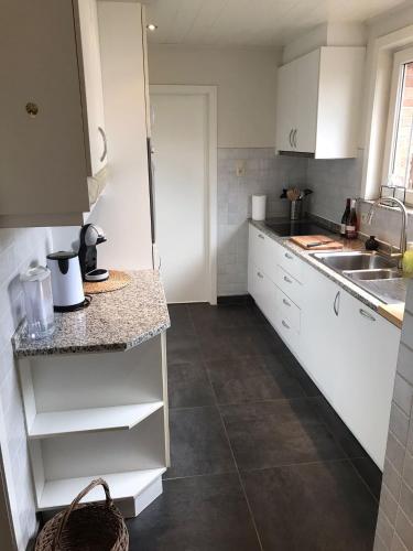 a kitchen with white cabinets and a counter top at De Bijenkorf in Damme