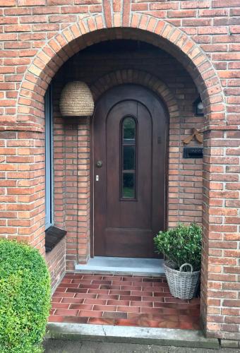 a brick house with a brown door and an archway at De Bijenkorf in Damme