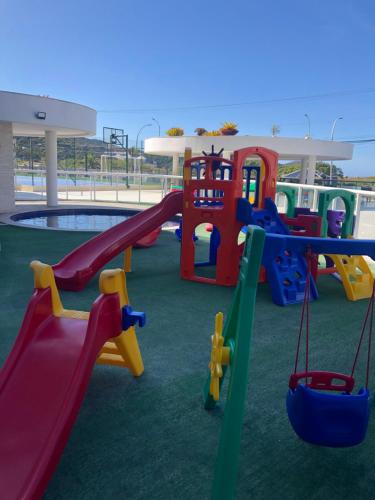 a playground with a slide and swings at Apto paraíso praia dos anjos in Arraial do Cabo