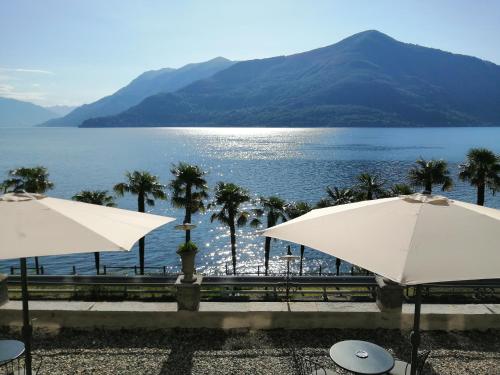 two white umbrellas in front of a body of water at Ca Meison in Cannobio