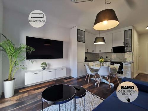 a living room with a table and a dining room at Apartamenty Mazurska Bryza nad Iławką in Iława