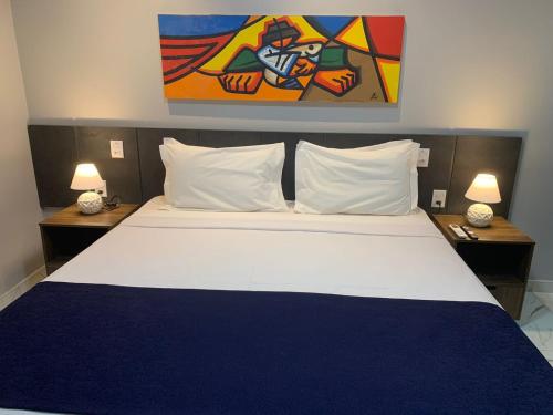 a bedroom with a large bed with two tables and two lamps at Netuanah Praia Hotel in João Pessoa