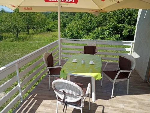 a table and chairs on a deck with an umbrella at House of the Rising Sun in Bosanska Gradiška