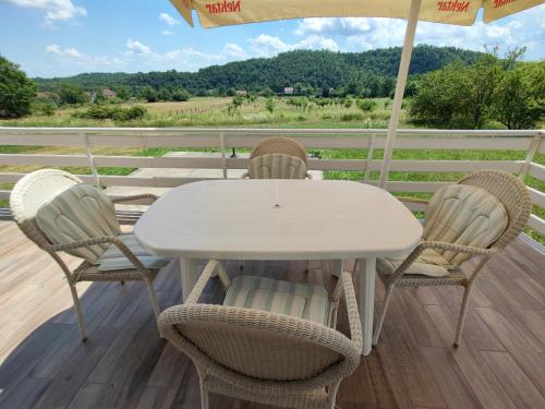 a white table and chairs on a deck with an umbrella at House of the Rising Sun in Bosanska Gradiška