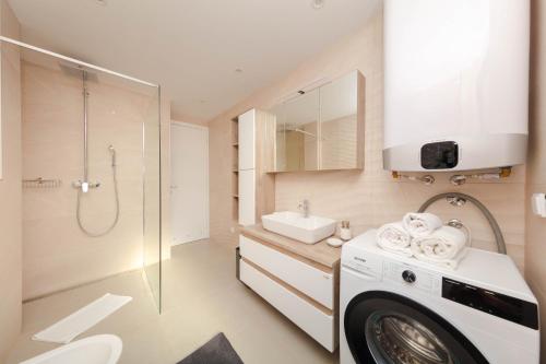 a bathroom with a sink and a washing machine at Resort Banjole - apartman Indigo in Banjole