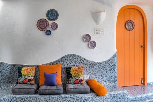 a couch with orange and blue pillows in a room at SaffronStays AsanjA Titaly, Murbad - hobbit inspired earth-shelter home with plunge pool in Murbād