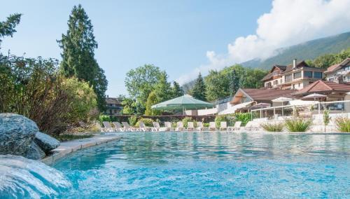 a pool at a resort with chairs and buildings at Residence Les Chataigniers in Saint-Jorioz