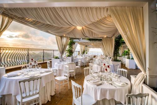un ristorante con tavoli e sedie bianchi e vista sull'oceano di San Lorenzo - Hotel & SPA a Lettere