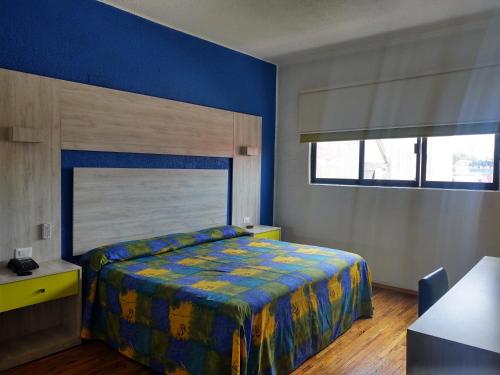 - une chambre avec un lit et un mur bleu dans l'établissement Hotel Gilbert, à Mexico