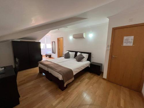 a bedroom with a large bed and a wooden floor at Vale do Zêzere Hotel in Manteigas