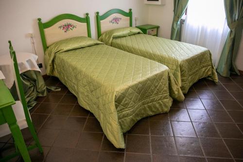 two beds with green covers in a room with a tile floor at La Villetta Food & Drink Rooms for Rent - No Reception - in LʼAquila