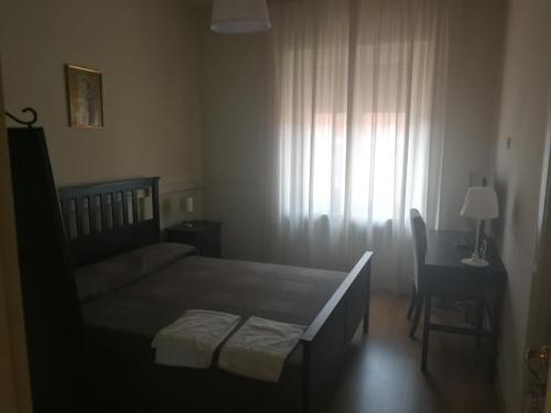 una camera con letto, scrivania e finestra di Casa per Ferie Suore Domenicane a Roma