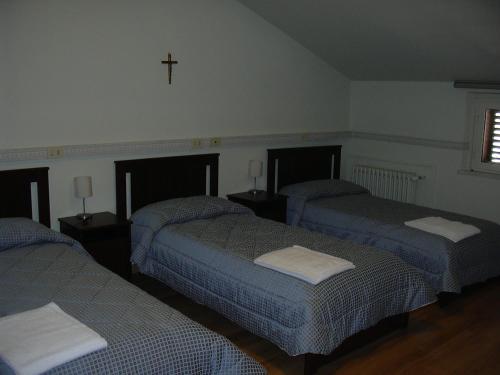 three beds in a room with a cross on the wall at Casa per Ferie Suore Domenicane in Rome