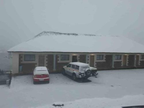 MokoengにあるHighlands Lodgeの雪の中の建物の前に停車する車