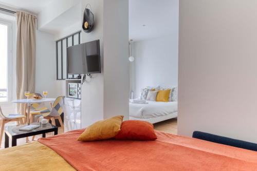 um quarto com uma cama com uma almofada laranja em New Large Studio in the Heart of Paris 12 em Paris